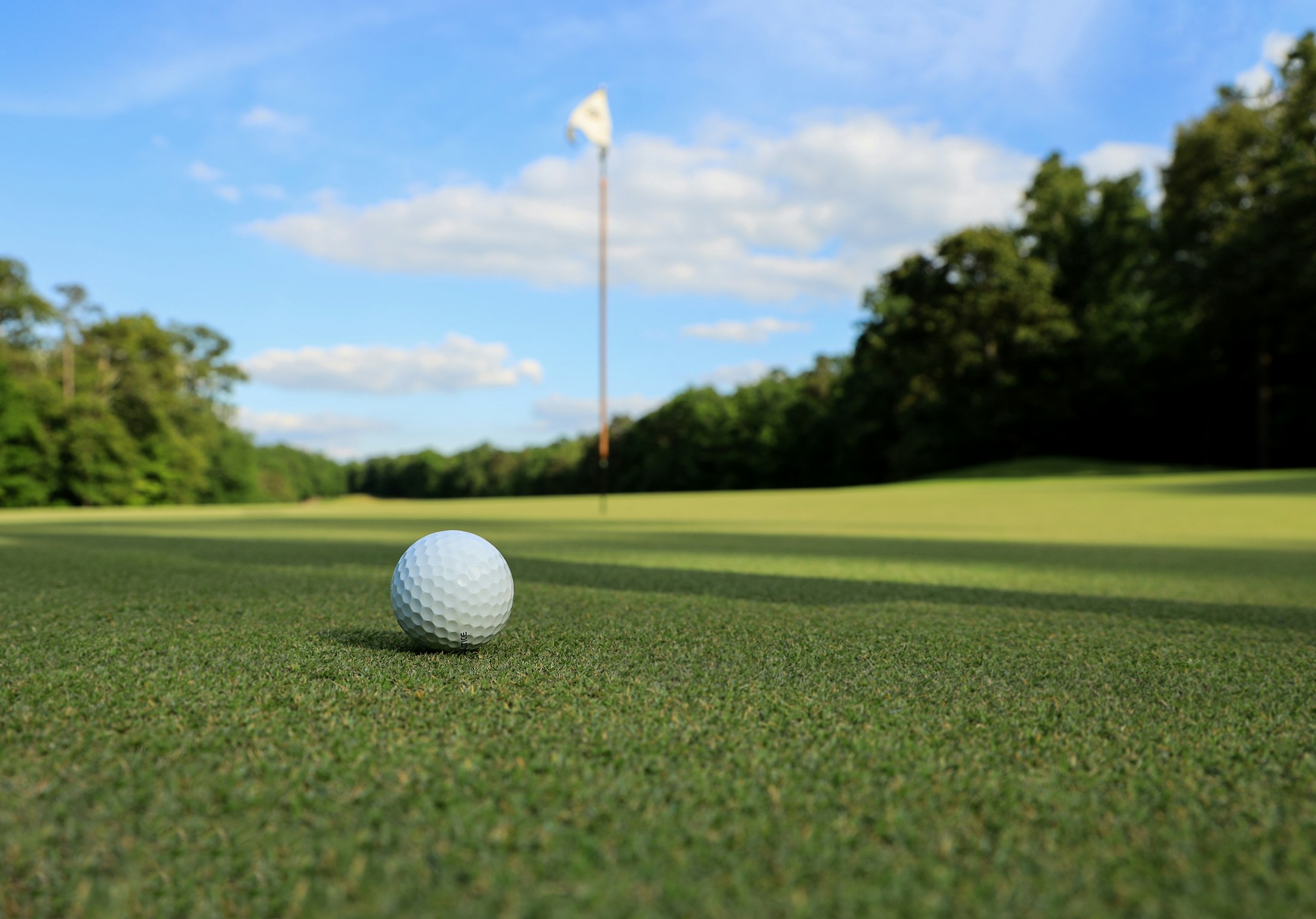 Golf ball on a green under blue sky